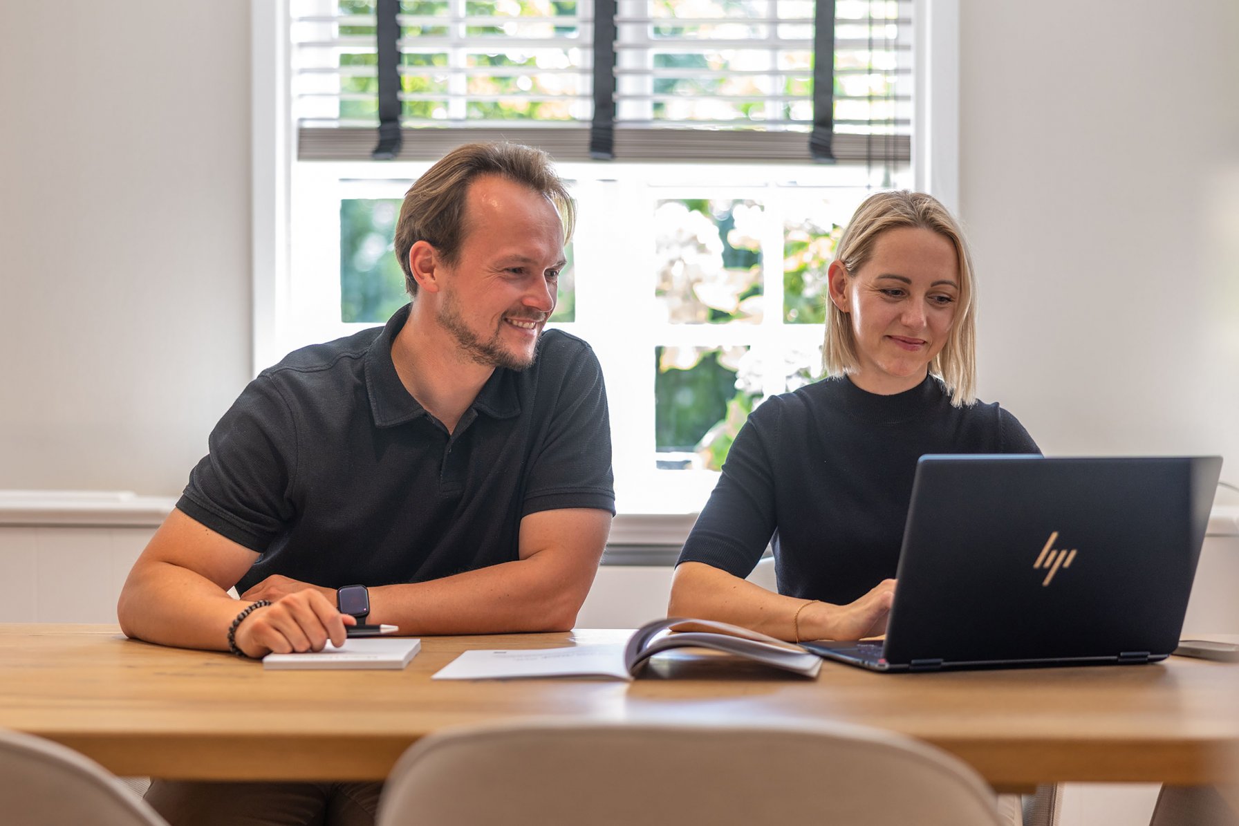 Zwei Personen von Mogck+Partner arbeiten an einem Tisch sitzend am Laptop